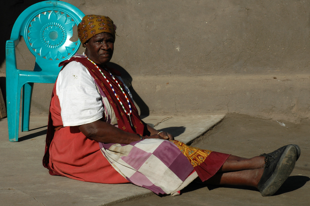 Middle-aged South African woman sitting on the ground.